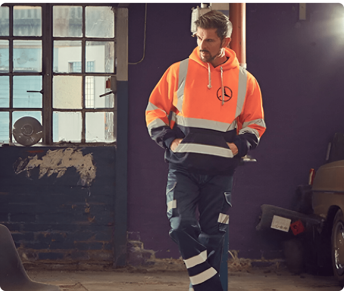 Man in bright orange safety gear standing indoors.