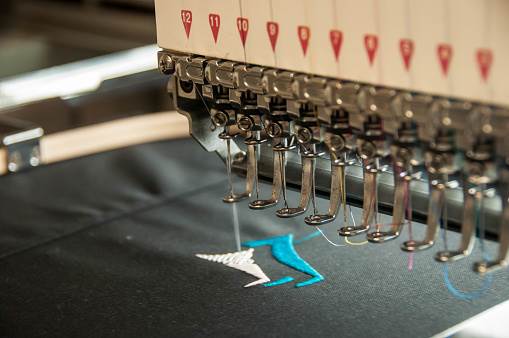 Close-up of embroidery machine stitching a colorful design on fabric.